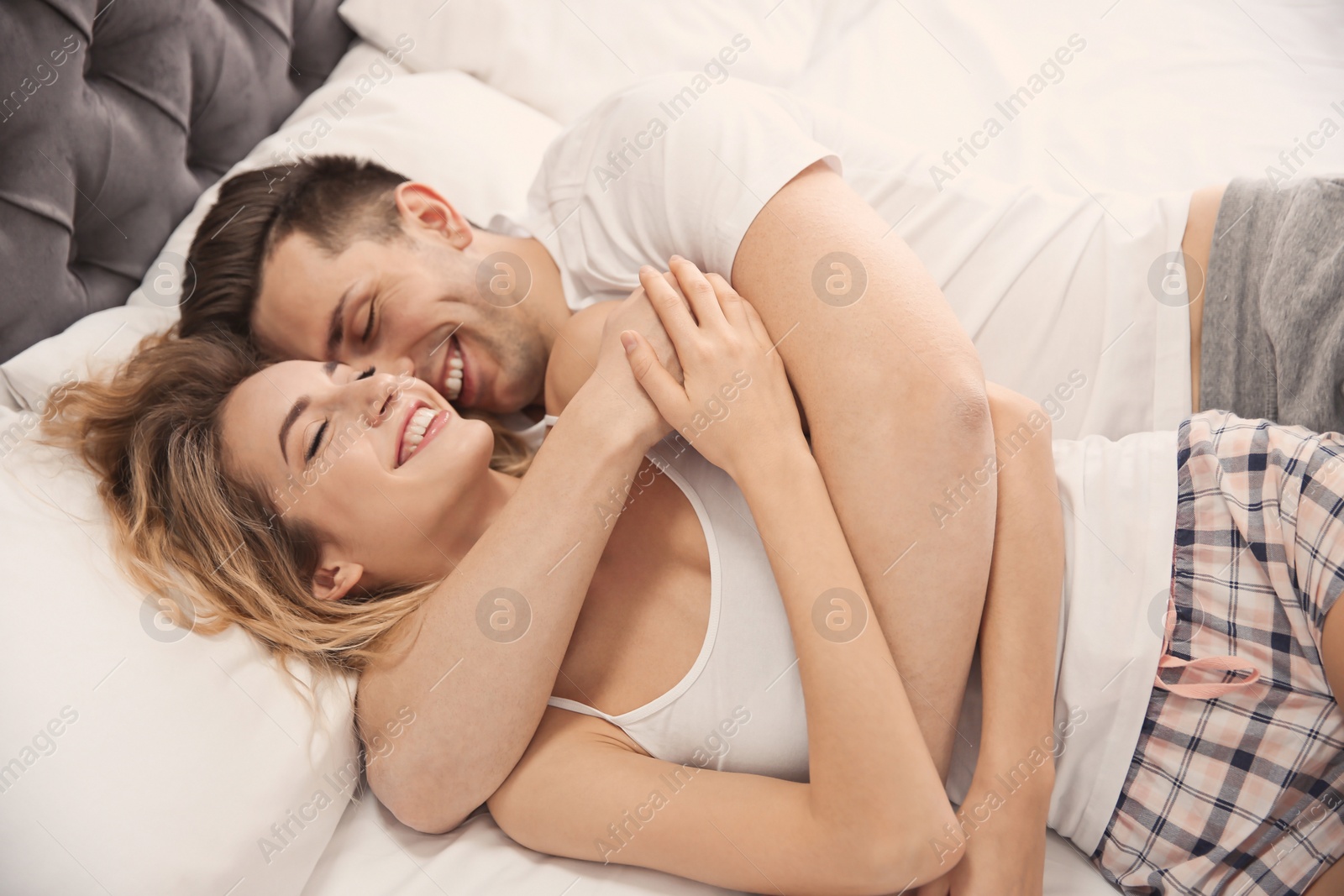 Photo of Lovely young couple hugging in bed at home