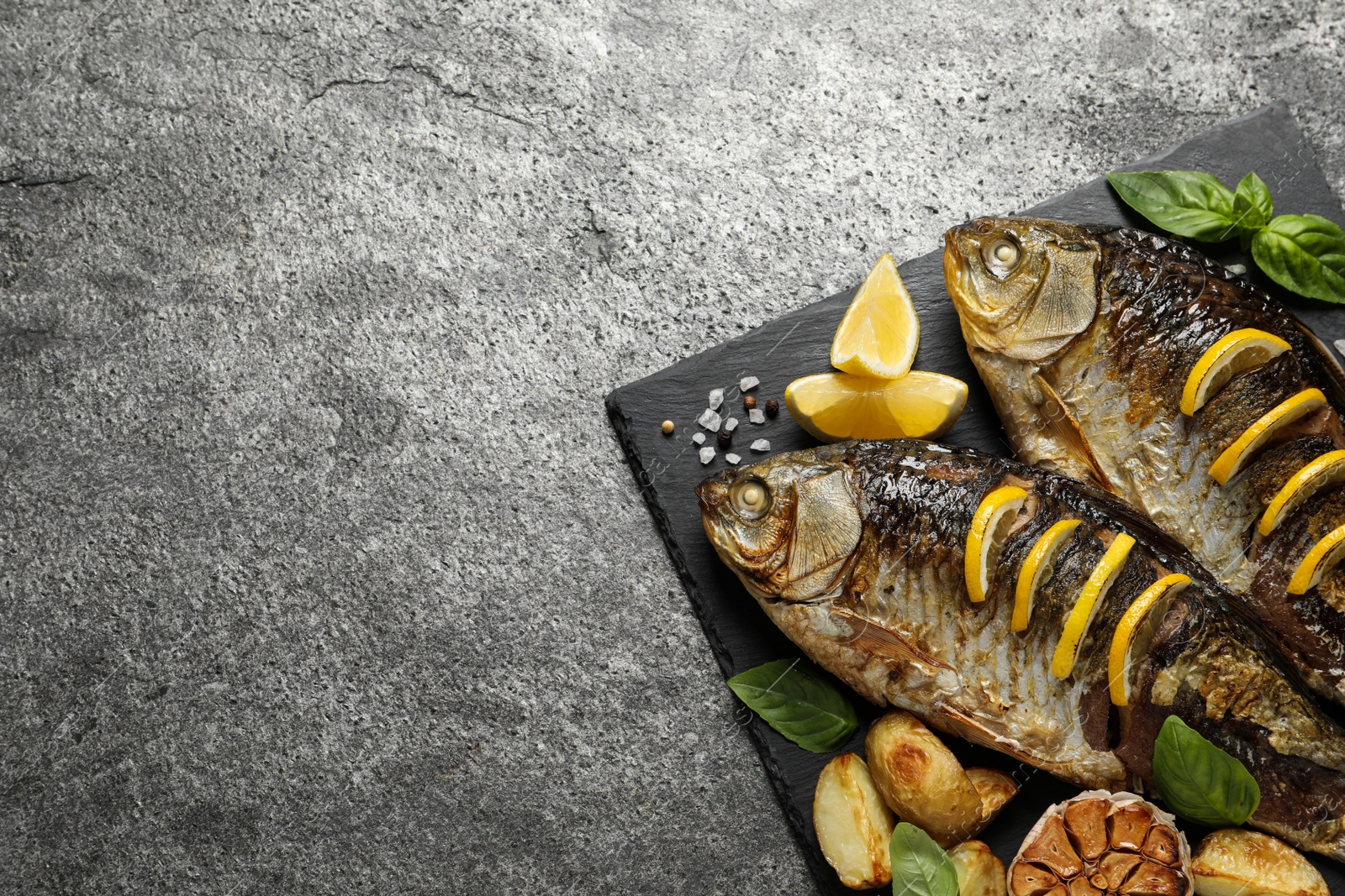 Photo of Tasty homemade roasted crucian carps served on grey table, top view and space for text. River fish