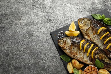 Tasty homemade roasted crucian carps served on grey table, top view and space for text. River fish Photo of Tasty homemade roasted crucian carps served on grey table, top view and space for text. River fish