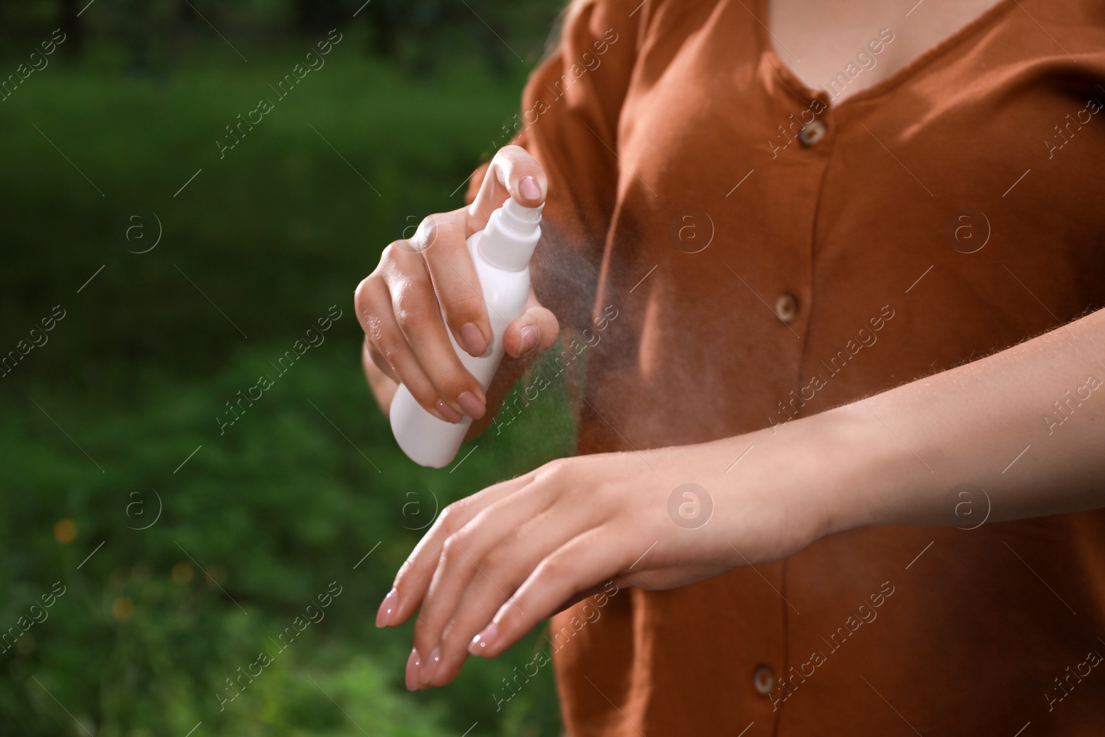 Woman applying insect repellent onto hand in park, closeup. Tick bites prevention Photo of Woman applying insect repellent onto hand in park, closeup. Tick bites prevention