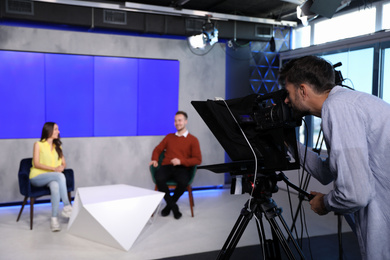 Presenters and video camera operator working in studio. News broadcasting Photo of Presenters and video camera operator working in studio. News broadcasting