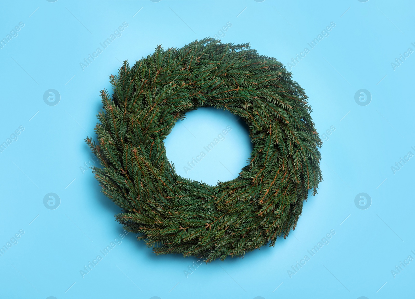 Christmas wreath made of fir branches on light blue background, top view Photo of Christmas wreath made of fir branches on light blue background, top view