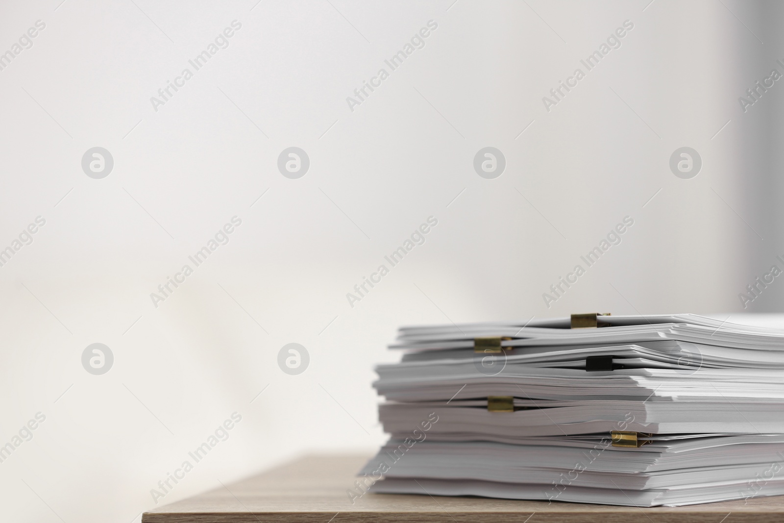 Stack of blank paper with binder clips on wooden table. Space for text Photo of Stack of blank paper with binder clips on wooden table. Space for text