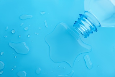 Drops of spilled water and plastic bottle on light blue background, top view Photo of Drops of spilled water and plastic bottle on light blue background, top view