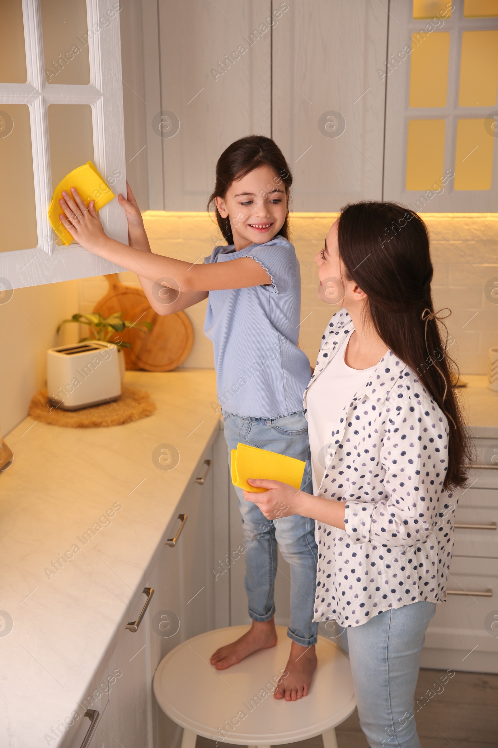 Mother and daughter cleaning up kitchen together at home Photo of Mother and daughter cleaning up kitchen together at home