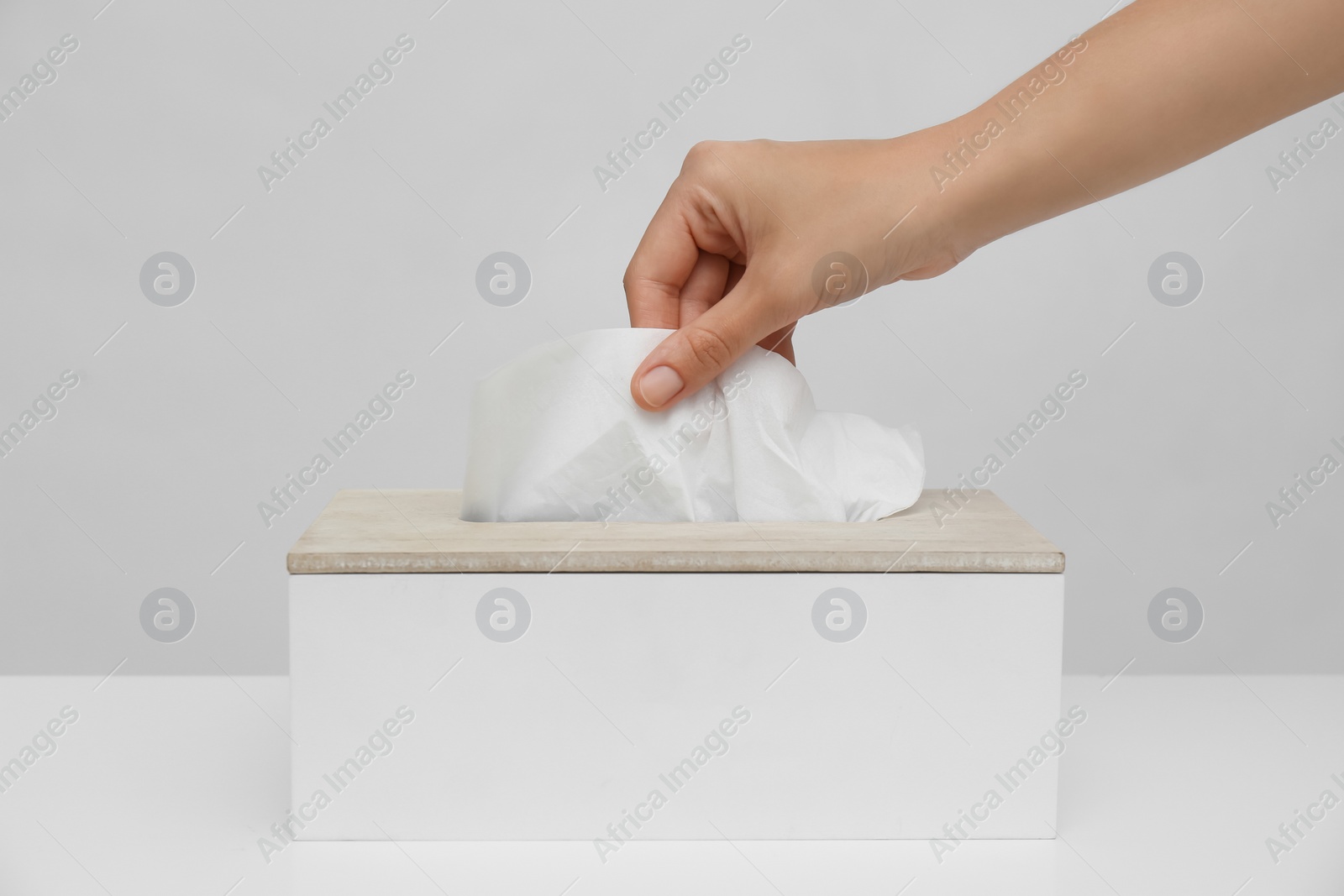 Woman taking paper tissue from holder on light background, closeup Photo of Woman taking paper tissue from holder on light background, closeup