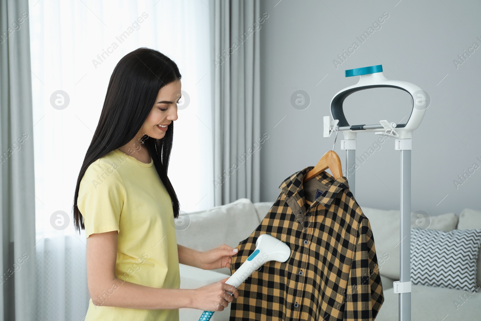 Woman steaming shirt on hanger at home Photo of Woman steaming shirt on hanger at home