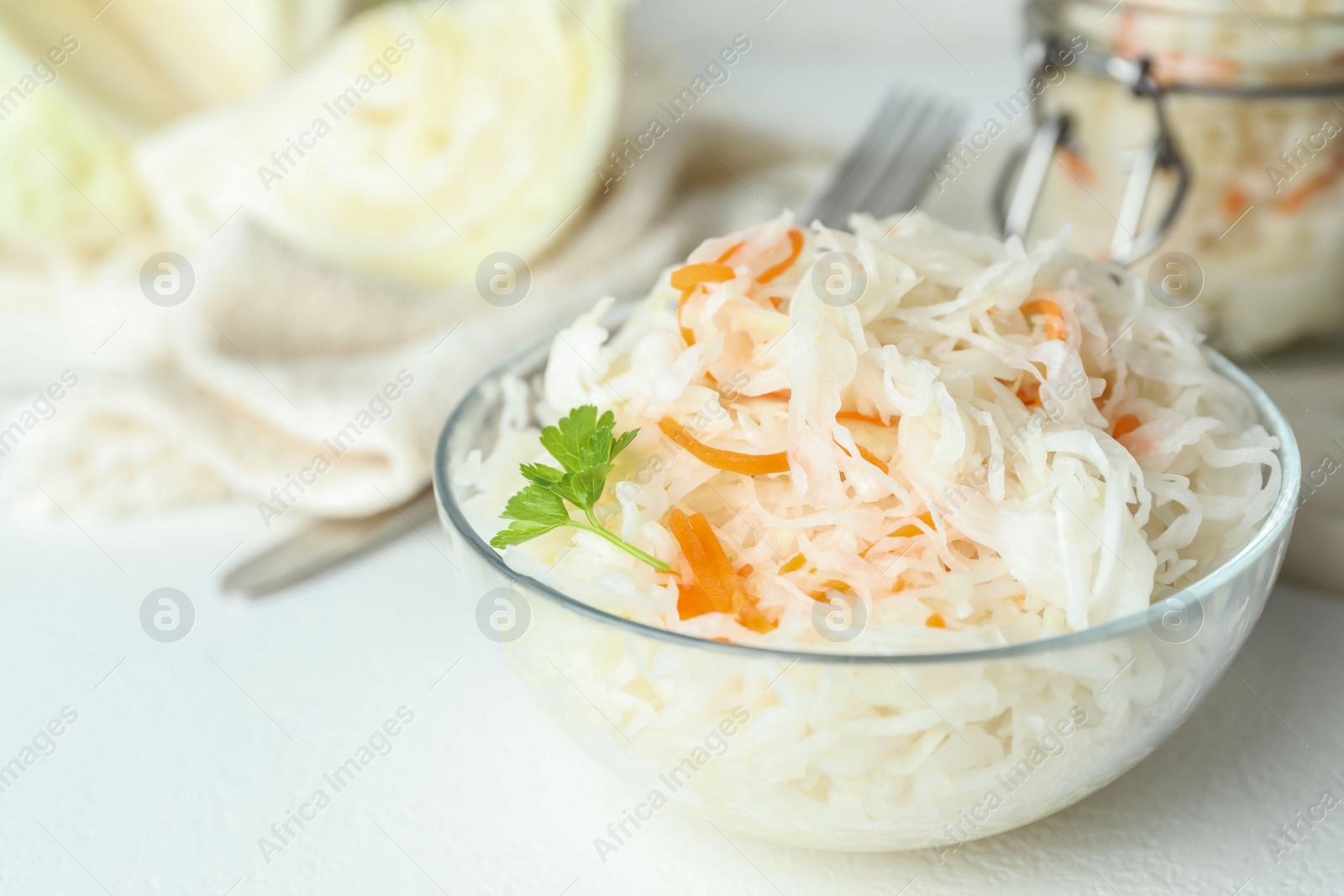 Glass bowl of tasty fermented cabbage on white table, closeup Photo of Glass bowl of tasty fermented cabbage on white table, closeup