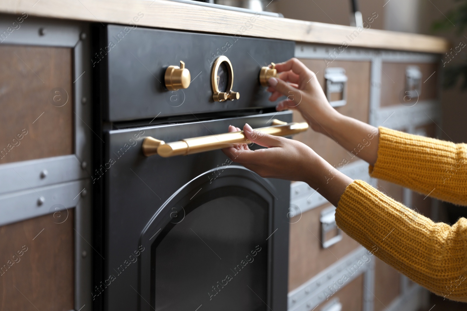 Woman using modern oven in kitchen, closeup Photo of Woman using modern oven in kitchen, closeup