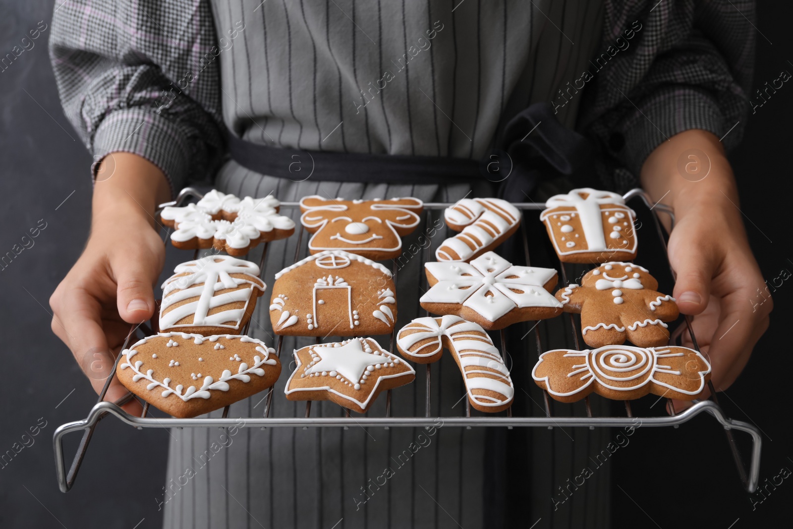Woman holding cooling rack with delicious homemade Christmas cookies on black background, closeup Photo of Woman holding cooling rack with delicious homemade Christmas cookies on black background, closeup