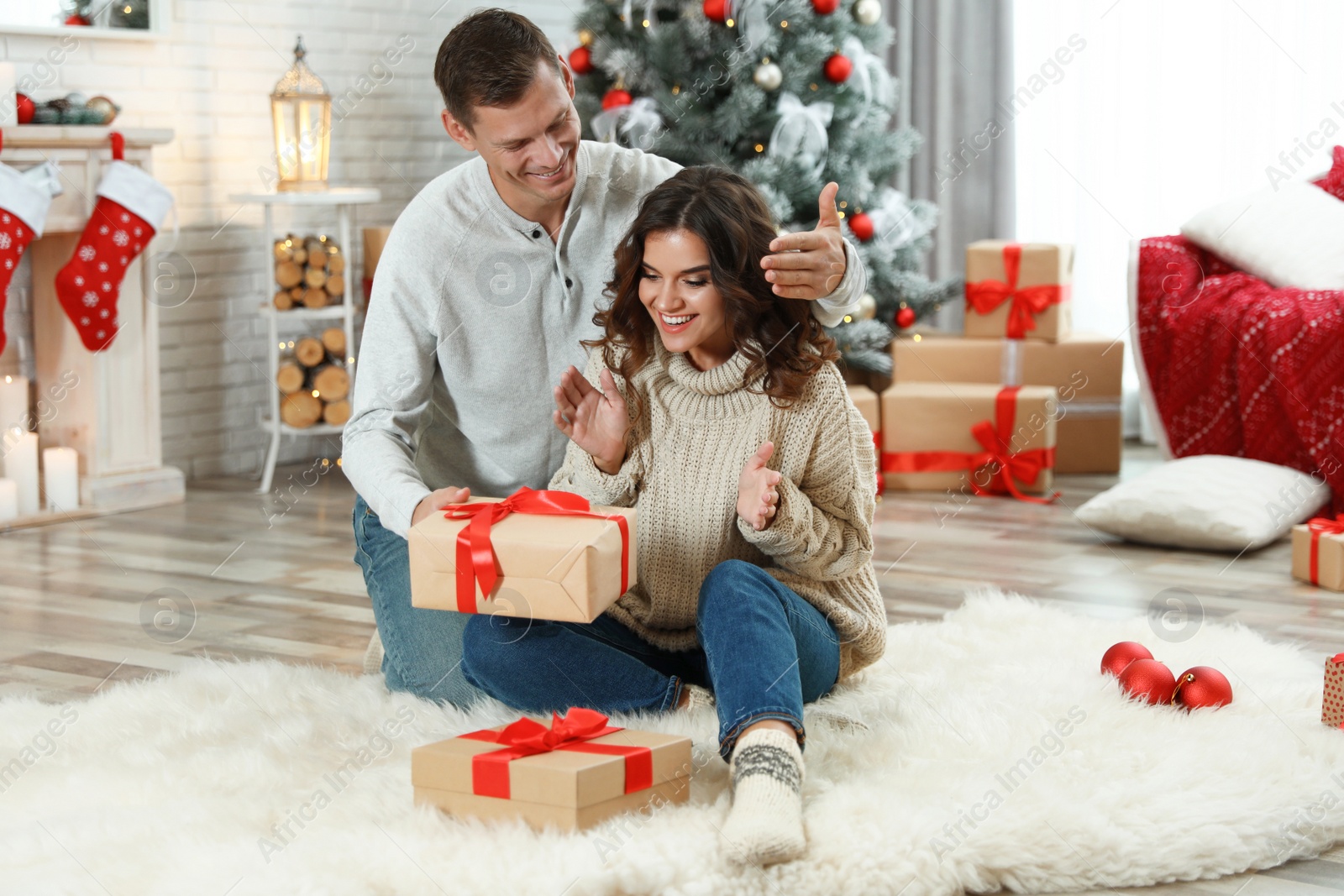 Man presenting Christmas gift to his girlfriend at home Image of Man presenting Christmas gift to his girlfriend at home