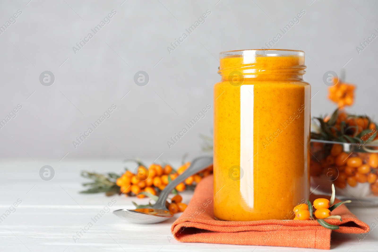 Delicious sea buckthorn jam and fresh berries on white wooden table. Space for text Photo of Delicious sea buckthorn jam and fresh berries on white wooden table. Space for text