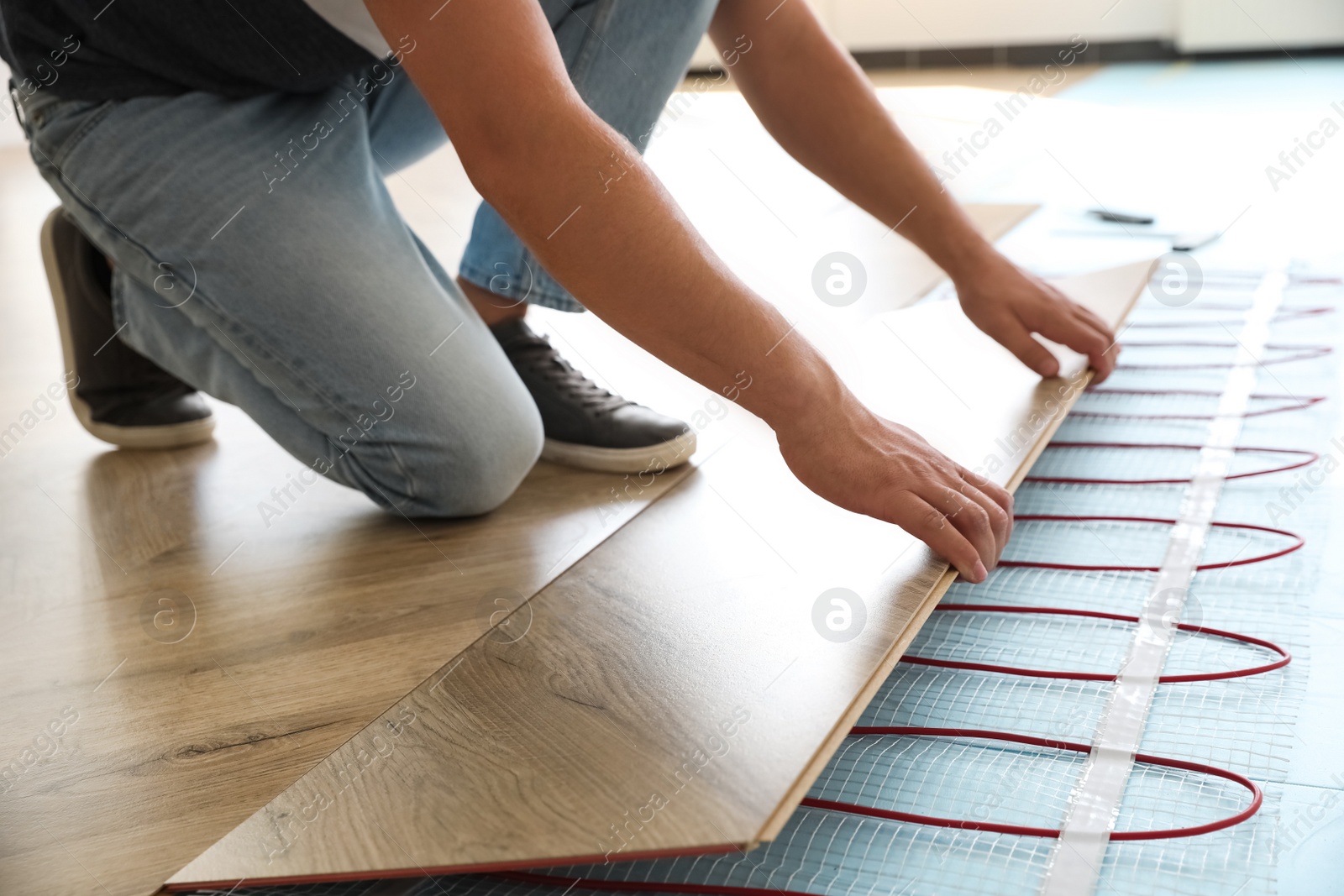 Professional contractor installing underfloor trace heating system indoors, closeup Photo of Professional contractor installing underfloor trace heating system indoors, closeup