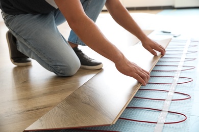Professional contractor installing underfloor trace heating system indoors, closeup Photo of Professional contractor installing underfloor trace heating system indoors, closeup