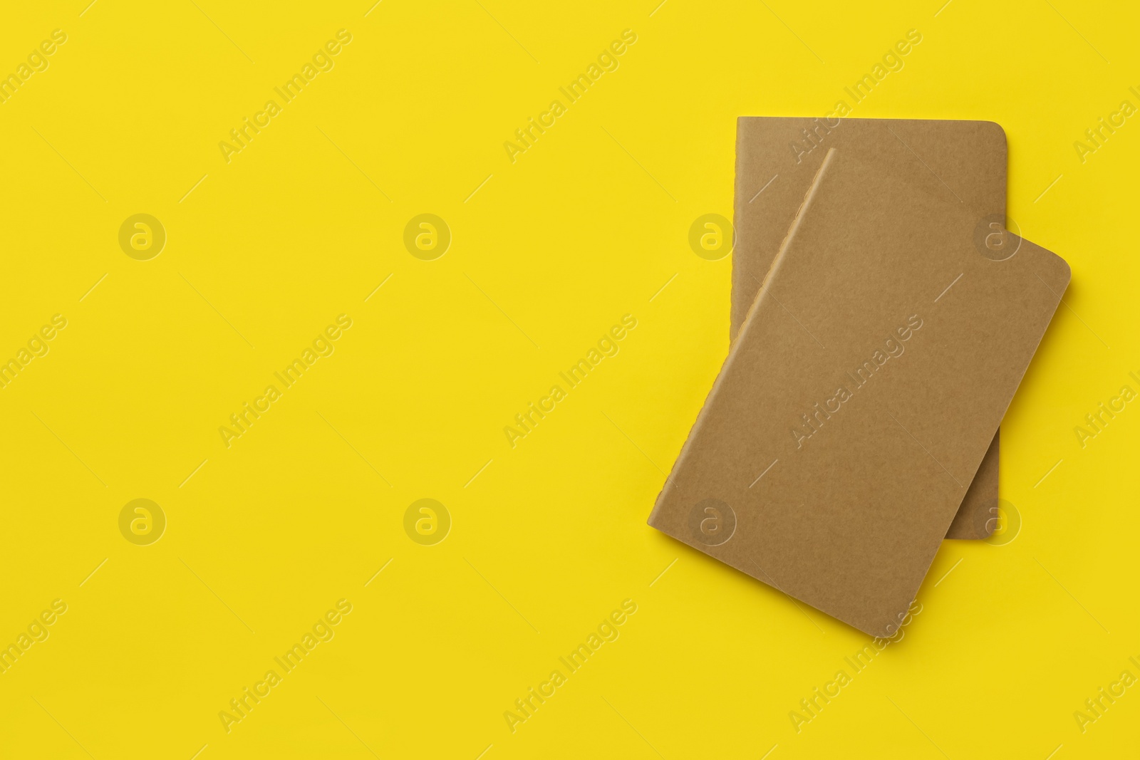 New stylish kraft planners on yellow background, top view. Space for text Photo of New stylish kraft planners on yellow background, top view. Space for text