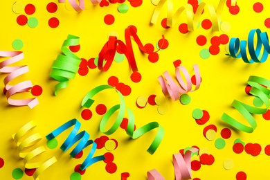 Colorful serpentine streamers and confetti on yellow background, flat lay Photo of Colorful serpentine streamers and confetti on yellow background, flat lay