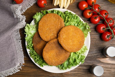 Delicious fried breaded cutlets, spices and cherry tomatoes on wooden table, flat lay Photo of Delicious fried breaded cutlets, spices and cherry tomatoes on wooden table, flat lay