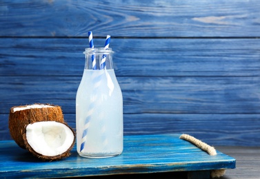 Bottle of coconut water with fresh nuts on wooden tray Photo of Bottle of coconut water with fresh nuts on wooden tray