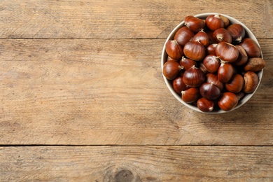 Fresh sweet edible chestnuts in bowl on wooden table, top view. Space for text Photo of Fresh sweet edible chestnuts in bowl on wooden table, top view. Space for text
