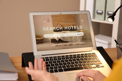 Woman searching hotel using laptop at table, closeup. Booking online service Image of Woman searching hotel using laptop at table, closeup. Booking online service