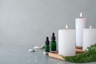 Burning candles and essential oil on grey marble table. Space for text Photo of Burning candles and essential oil on grey marble table. Space for text