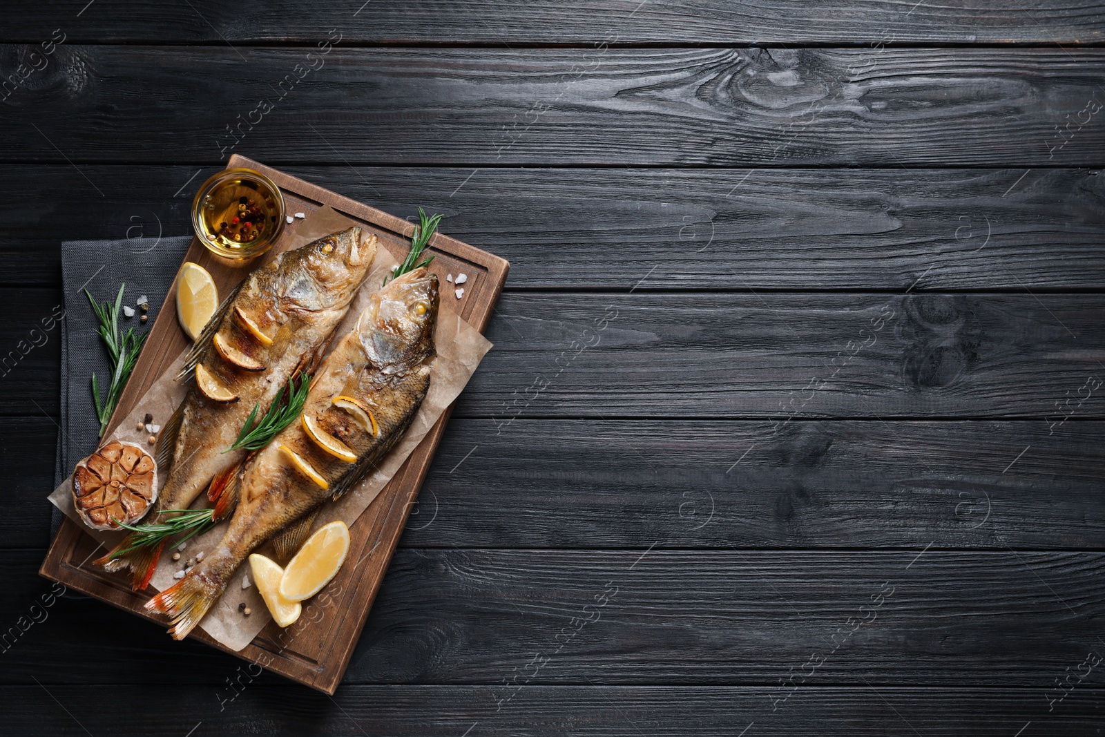 Tasty homemade roasted perches on black wooden table, top view and space for text. River fish Photo of Tasty homemade roasted perches on black wooden table, top view and space for text. River fish