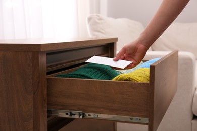 Woman putting scented sachet into drawer with clothes, closeup Photo of Woman putting scented sachet into drawer with clothes, closeup