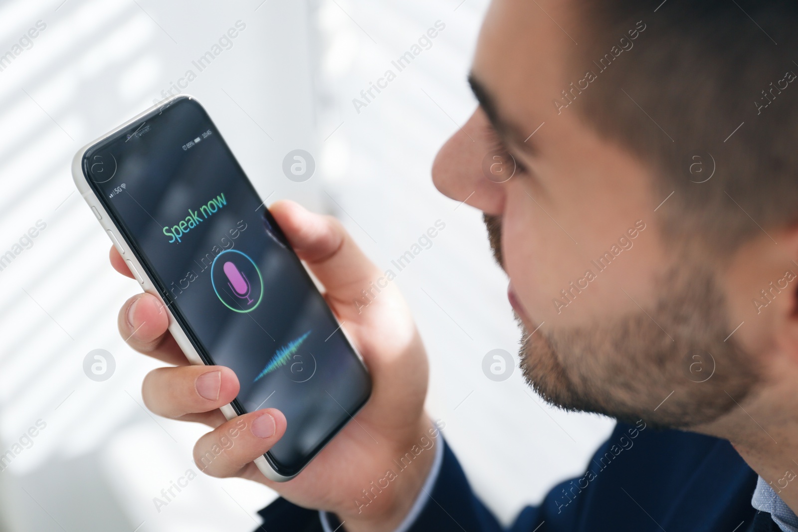 Young man using voice search on smartphone indoors, closeup Photo of Young man using voice search on smartphone indoors, closeup