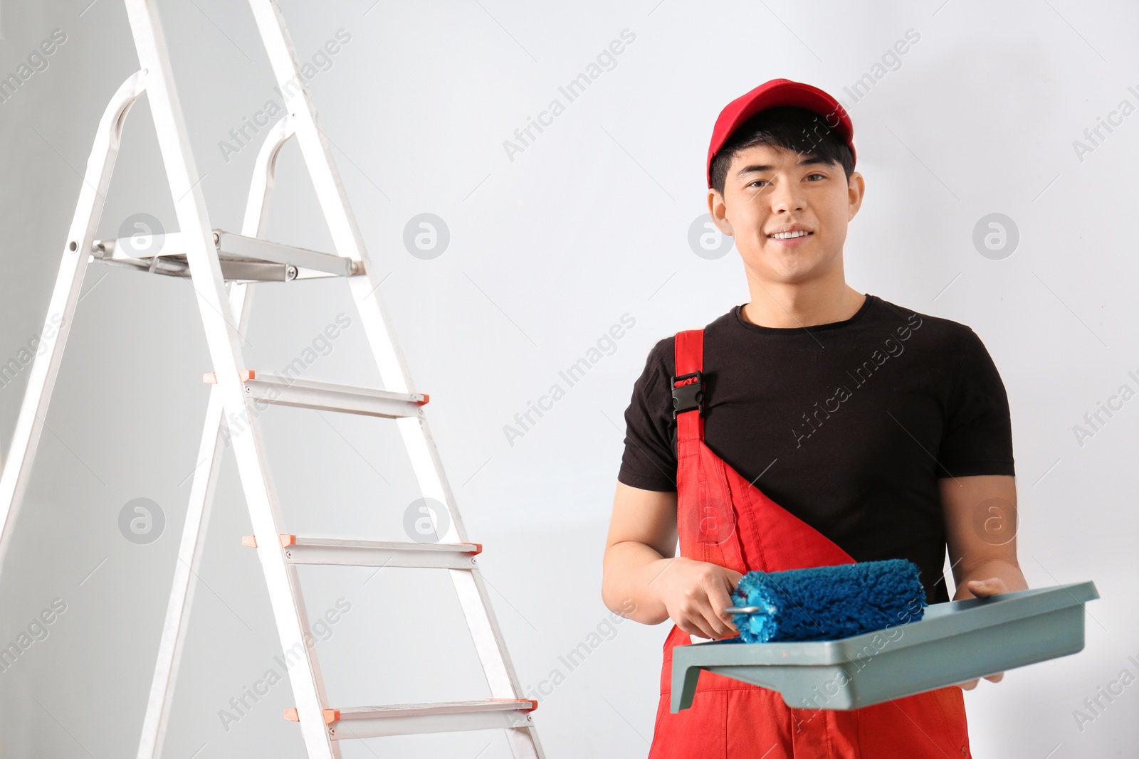 Male decorator with paint and roller indoors Photo of Male decorator with paint and roller indoors