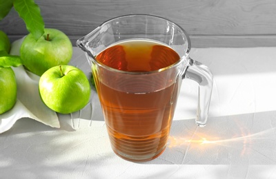 Jug with juice and fresh apples on table Photo of Jug with juice and fresh apples on table