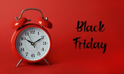 Phrase Black Friday and alarm clock on red background Photo of Phrase Black Friday and alarm clock on red background