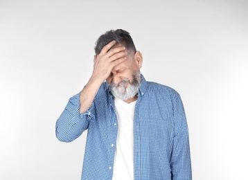 Man suffering from headache on light background Photo of Man suffering from headache on light background