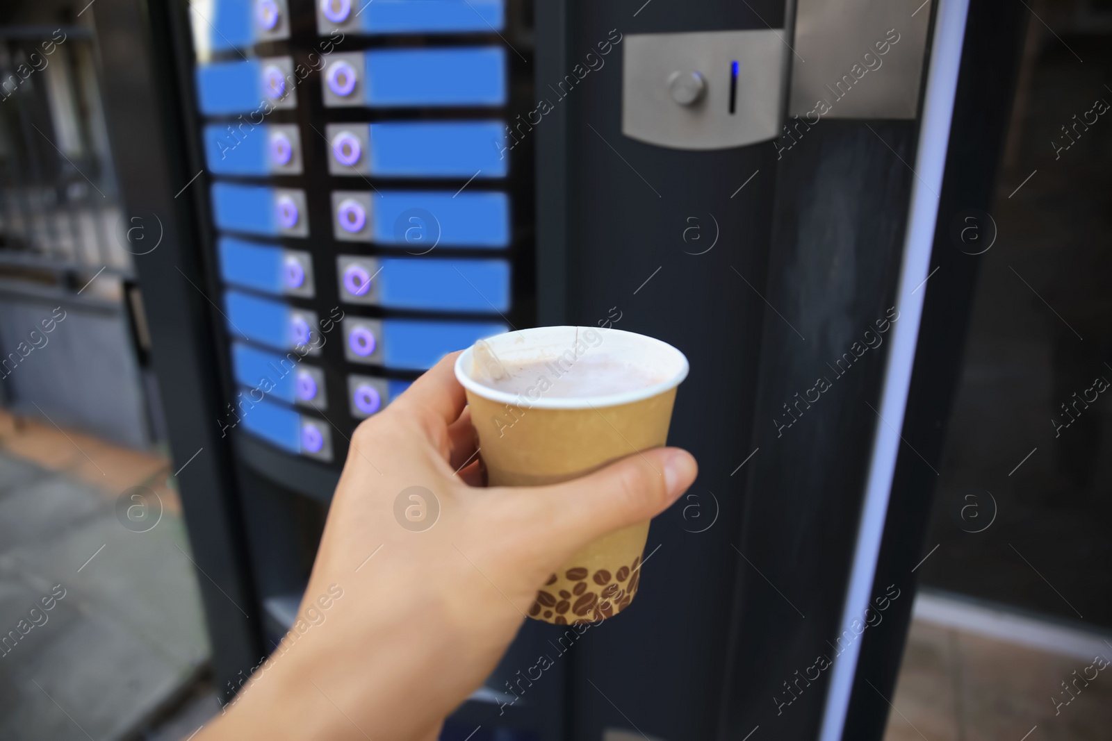 Photo of Man holding paper cup with hot drink near coffee vending machine