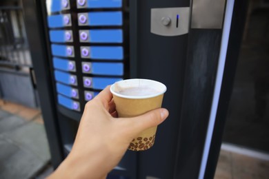 Man holding paper cup with hot drink near coffee vending machine Photo of Man holding paper cup with hot drink near coffee vending machine