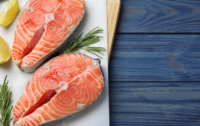 Top view of fresh raw salmon with lemon and rosemary on blue wooden table, space for text. Fish delicacy Photo of Top view of fresh raw salmon with lemon and rosemary on blue wooden table, space for text. Fish delicacy