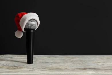 Microphone with Santa hat on white table against black background, space for text. Christmas music Photo of Microphone with Santa hat on white table against black background, space for text. Christmas music