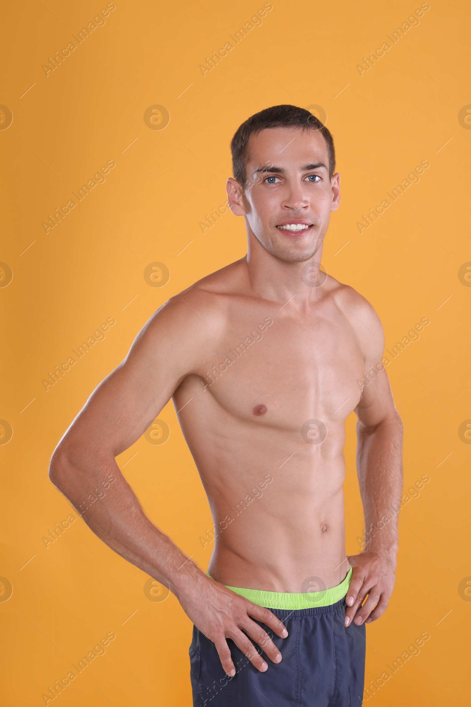 Handsome shirtless man with slim body on yellow background Photo of Handsome shirtless man with slim body on yellow background