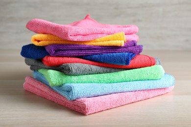 Stack of colorful microfiber cloths on light wooden table, closeup Photo of Stack of colorful microfiber cloths on light wooden table, closeup