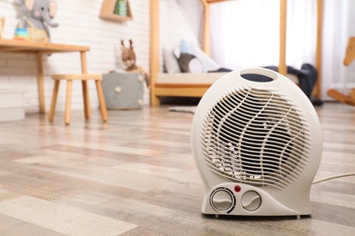 Modern electric fan heater on floor at home. Space for text Photo of Modern electric fan heater on floor at home. Space for text