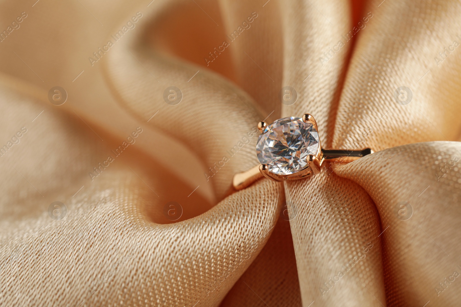 Beautiful engagement ring with gemstone on beige fabric, closeup Photo of Beautiful engagement ring with gemstone on beige fabric, closeup