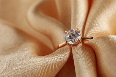 Beautiful engagement ring with gemstone on beige fabric, closeup Photo of Beautiful engagement ring with gemstone on beige fabric, closeup