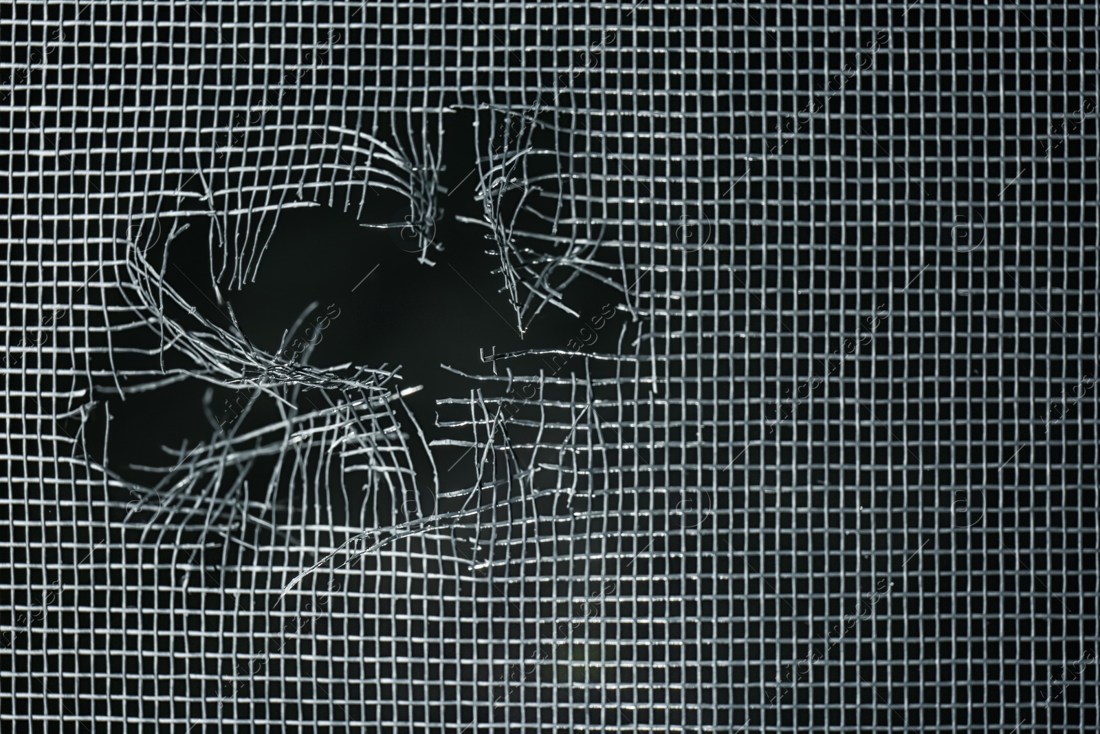 Photo of Torn window screen against black background, closeup