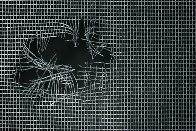 Torn window screen against black background, closeup Photo of Torn window screen against black background, closeup