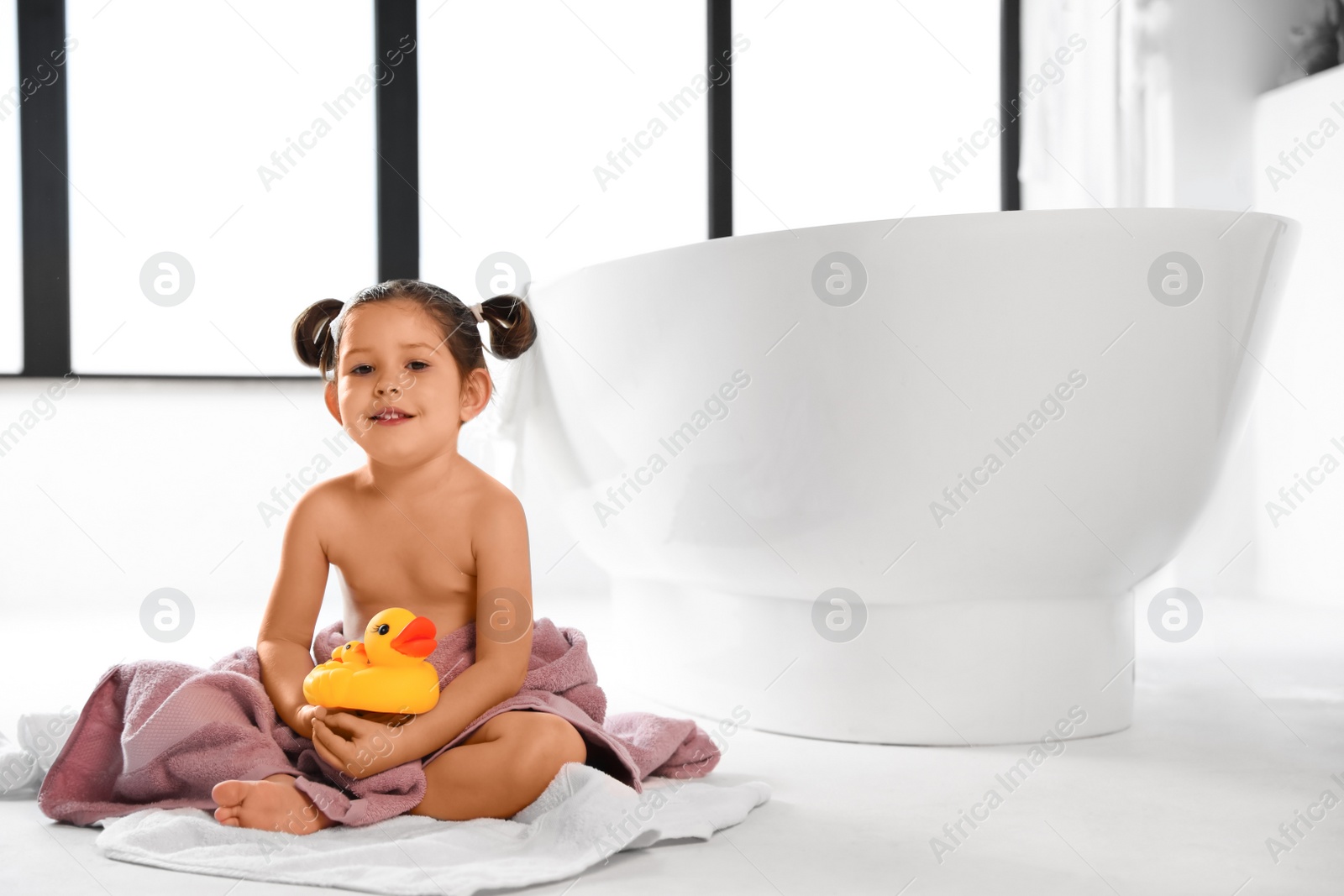 Photo of Cute little girl near tub in bathroom. Space for text