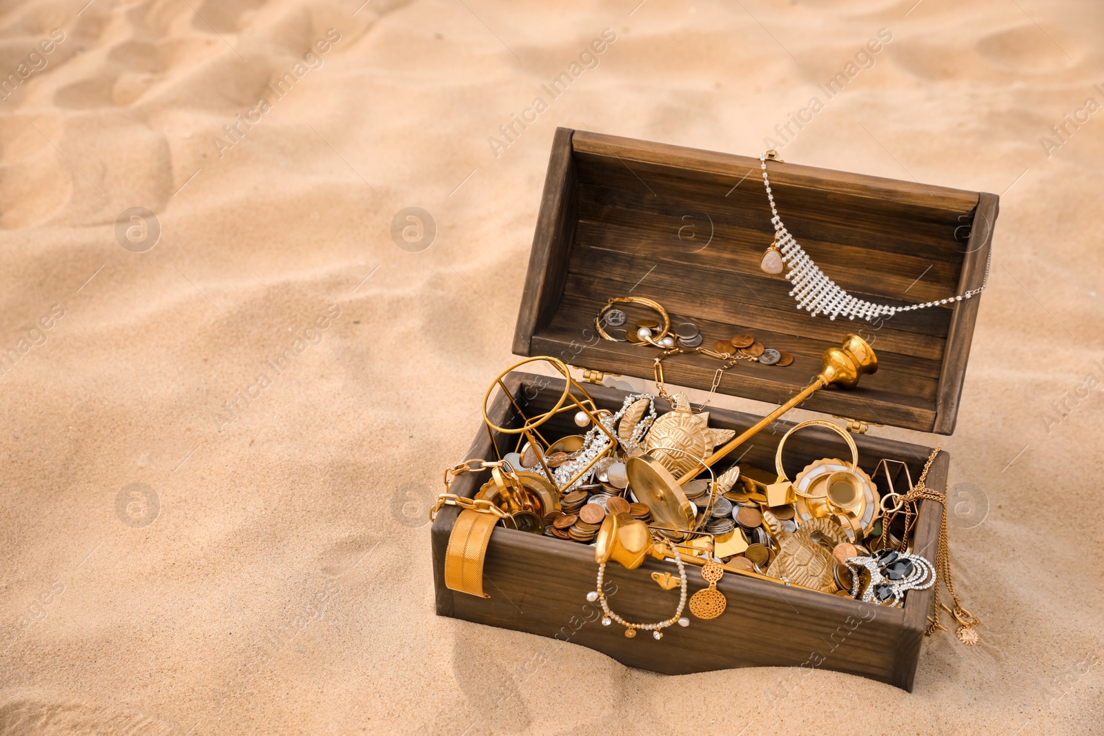 Open wooden treasure chest on sand, space for text Photo of Open wooden treasure chest on sand, space for text