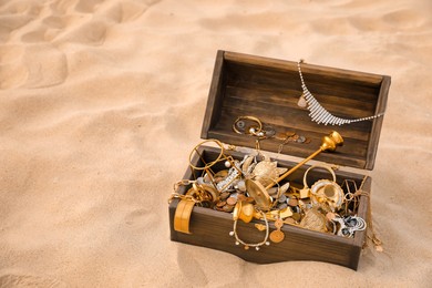 Open wooden treasure chest on sand, space for text Photo of Open wooden treasure chest on sand, space for text