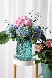 Beautiful hortensia flowers in vase on stand indoors Photo of Beautiful hortensia flowers in vase on stand indoors