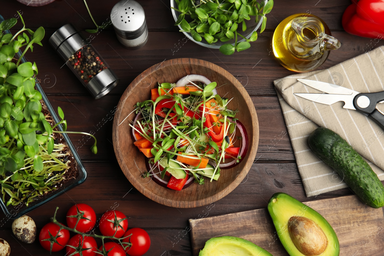 Salad with fresh organic microgreen in bowl and ingredients on wooden table, flat lay Photo of Salad with fresh organic microgreen in bowl and ingredients on wooden table, flat lay