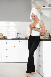 Beautiful young woman with towel, phone and glass of juice in kitchen Photo of Beautiful young woman with towel, phone and glass of juice in kitchen