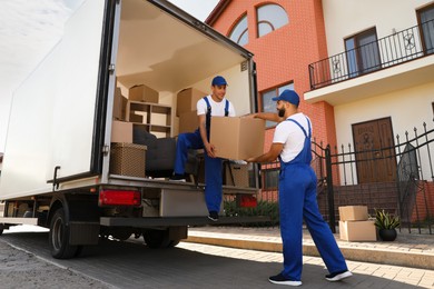 Workers unloading boxes from van outdoors. Moving service Photo of Workers unloading boxes from van outdoors. Moving service